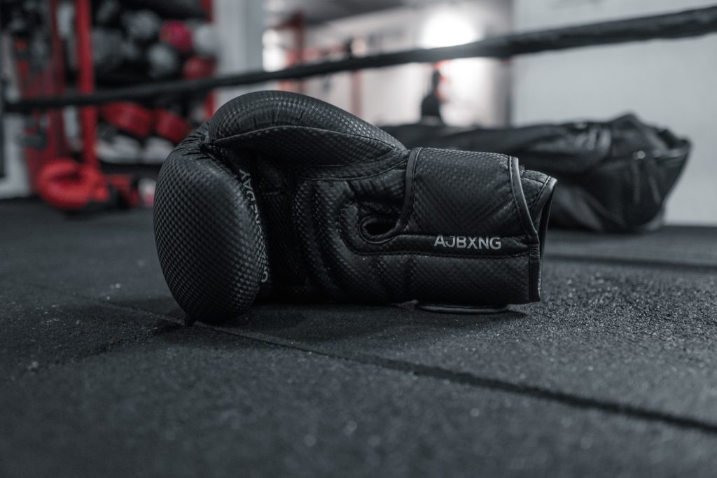 black and white boxing glove sitting on the floor of a boxing ring